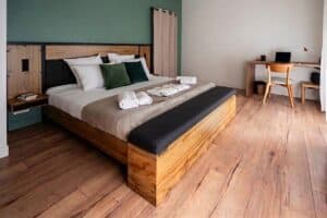 Chambre du premier étage de La Maison Cabane à Cholet avec lit King Size en bois, banc de lit et coin bureau.