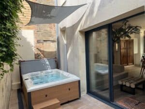 Jacuzzi privatif dans la cour intérieure de La Maison Cabane à Cholet, sous un voile d'ombrage